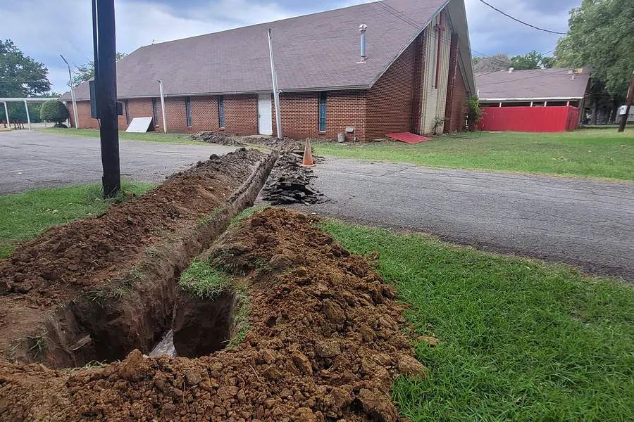 Drainage trench dug across a North Texas lawn for a French drain installation