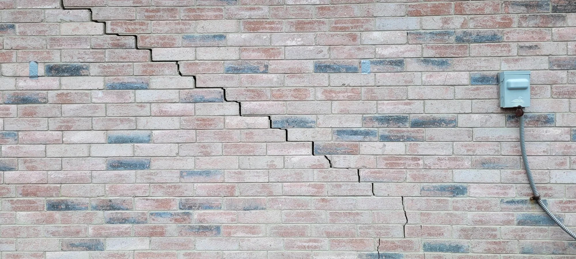 Stair-step crack running through the brick veneer of a Dallas-Fort Worth home