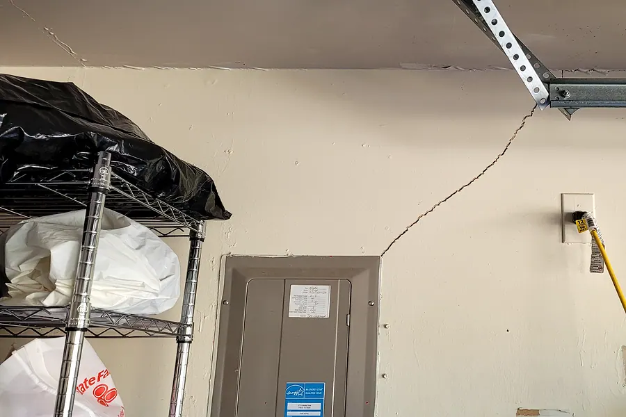 Diagonal drywall crack running from the corner of an interior door frame