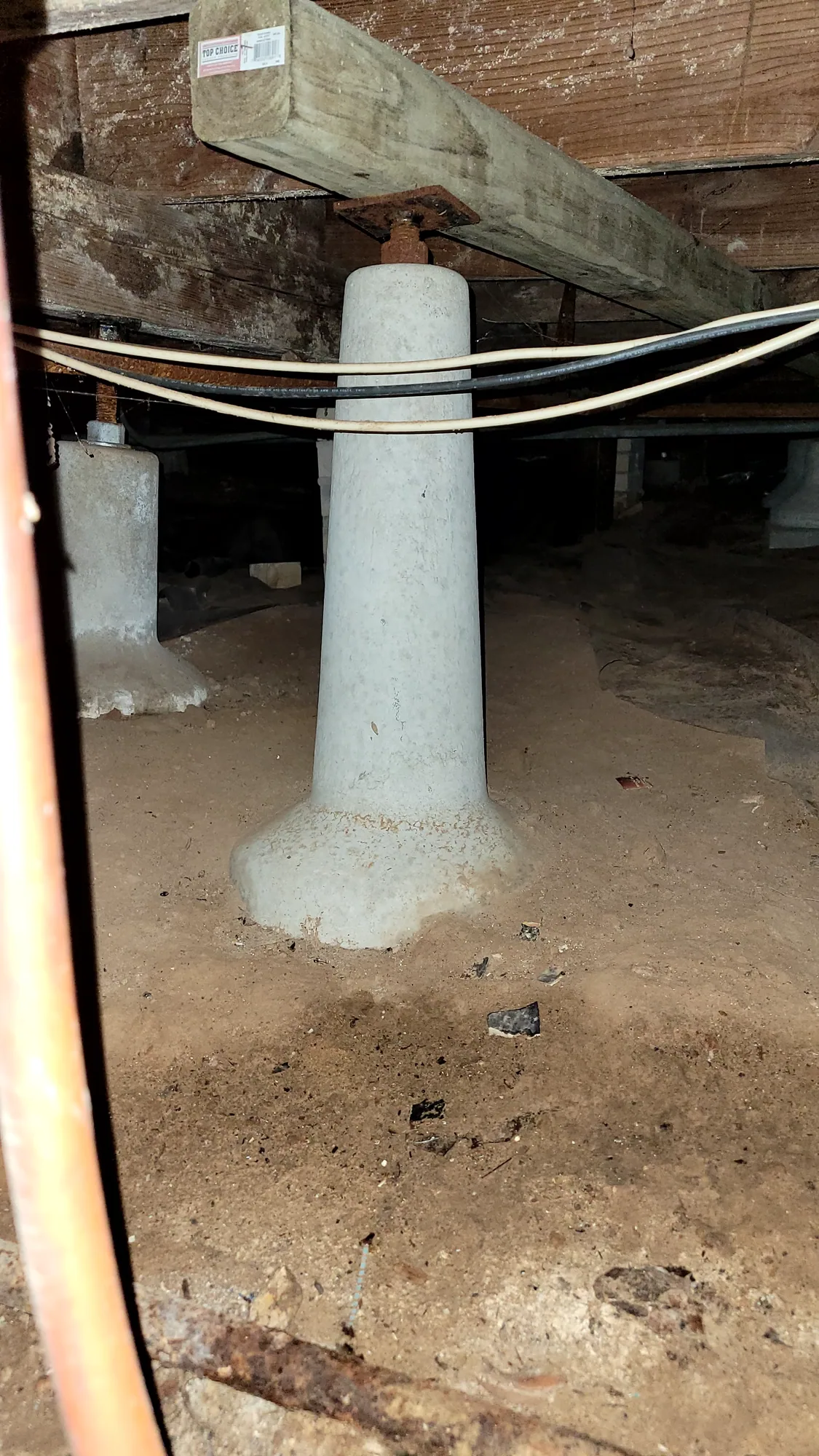 Concrete pier supporting a wood beam in the crawl space of an older pier-and-beam home