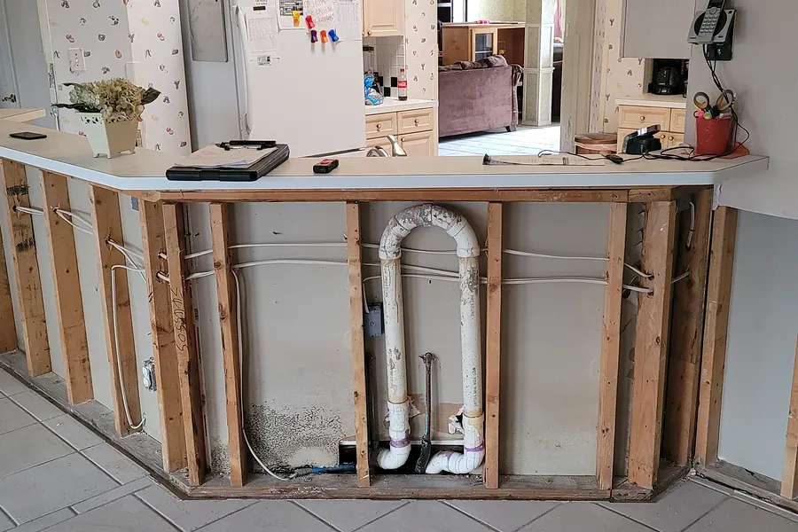 Wall opened to expose water supply lines during water damage mitigation in a DFW home