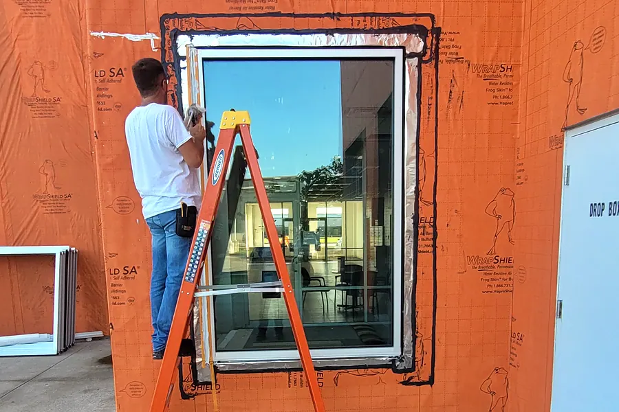 Installer setting a replacement window in an opening on a North Texas building